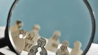 Business recruitment or hiring photo concept. Looking for talent. Icons of candidates are standing on open newspaper under magnifier. Business recruitment or hiring photo concept. Looking for talent. Icons of candidates are standing on open newspaper under magnifier.