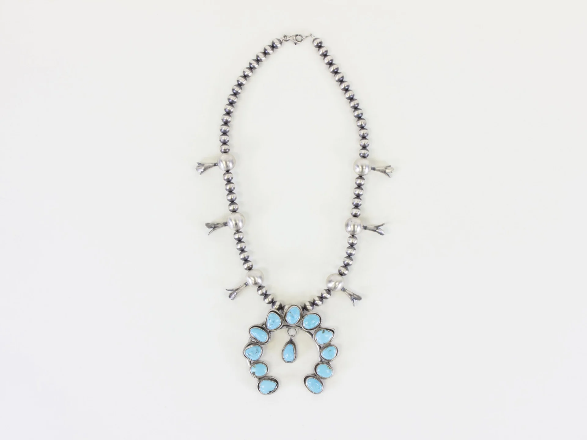A sterling silver squash blossom necklace featuring Kingman turquoise, crafted by Navajo silversmith Harrison Yazzie, purchased and provided by El Palacio Magazine and the Museum of Indian Arts & Culture.