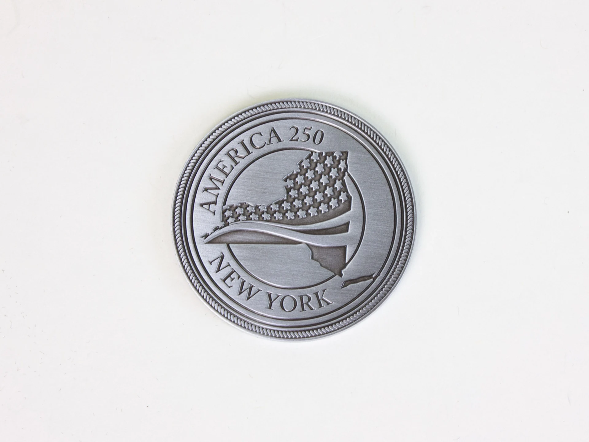New York's contribution to the America 250 time capsule, which is a coin that reads “Kingston, NY 1777 New York’s First Capital” on the back.
