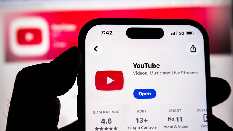 hand holding an iphone displaying the youtube app store page