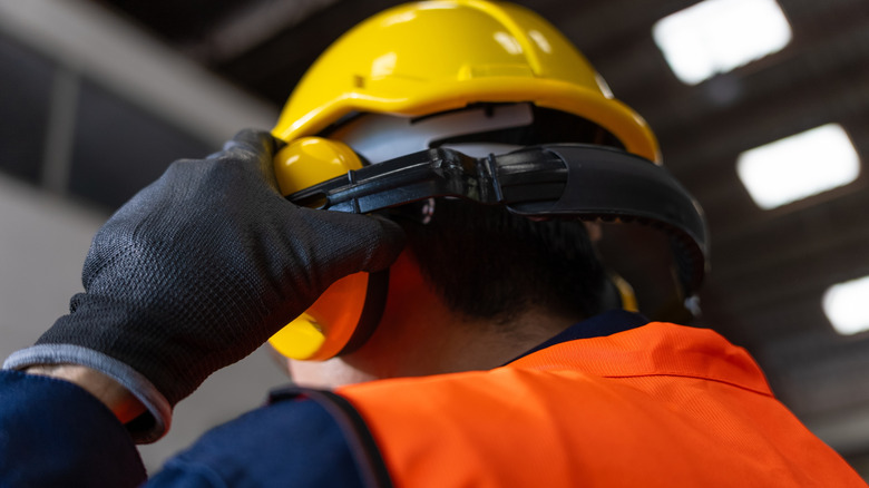 Factory worker wearing a protective safety helmet and earmuffs
