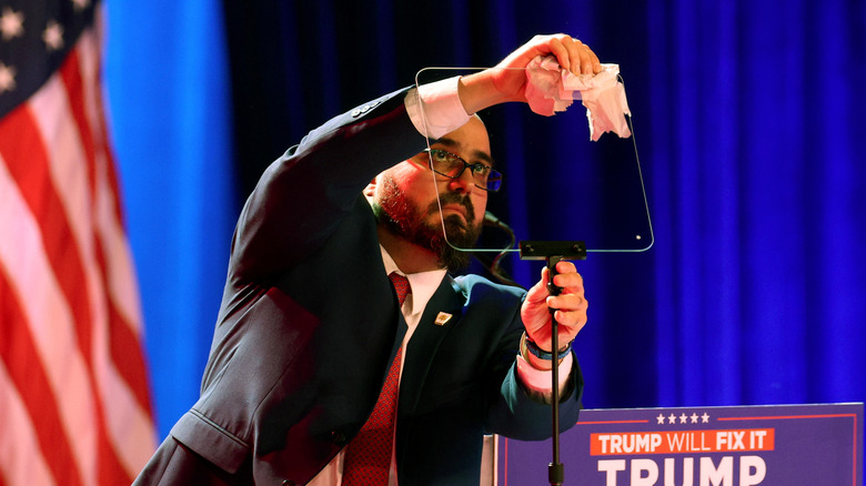 A teleprompter operator cleaning a teleprompter before a Trump rally.